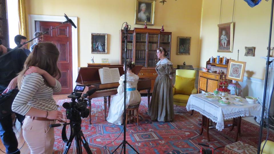 Filming in the Yellow Drawing Room at Tatton Park, showing a piano lesson in progress and the film crew